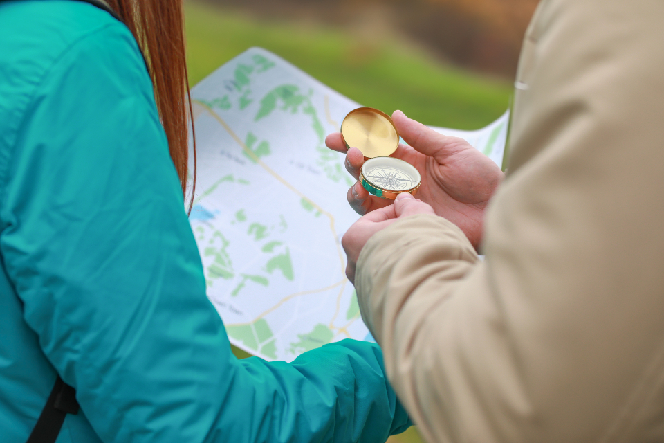 Two people reading a map with a compass, working out which way to go